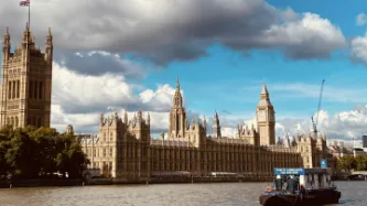 UK Westminister Abbey on a sunny day, with a boat on the thames in the foreground